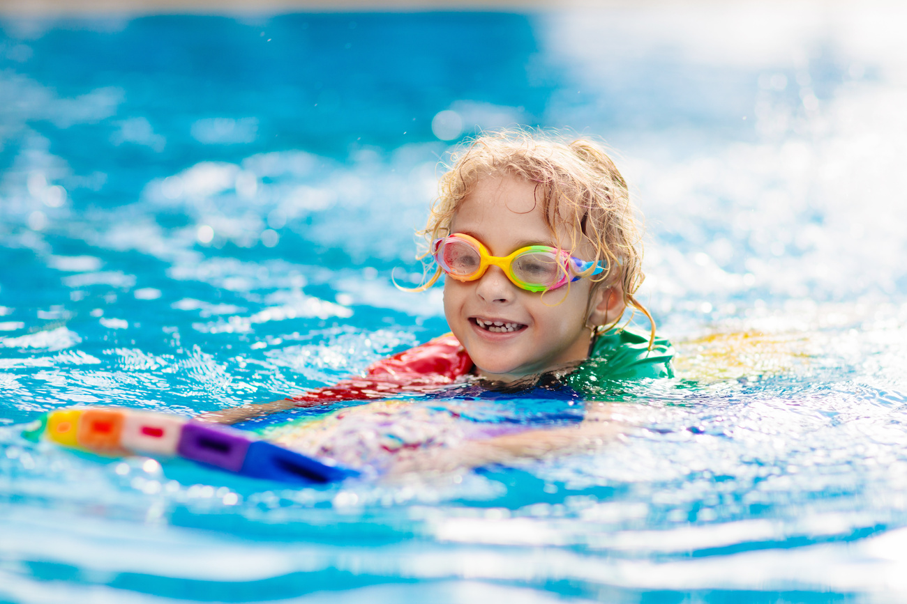 Child learning to swim. Kids in swimming pool.